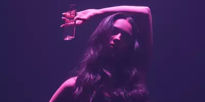 Olivia Rodrigo，粉色光下有飘逸的长发，装着 Idole Power 香水 Intense