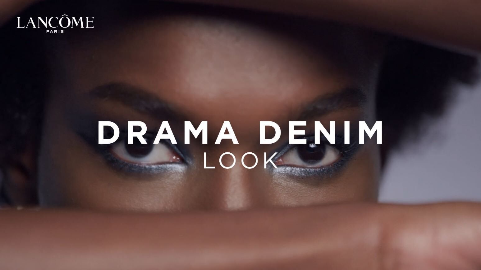 女士展示如何为深色肌肤打造戏剧牛仔灵感的眼妆和眼影。